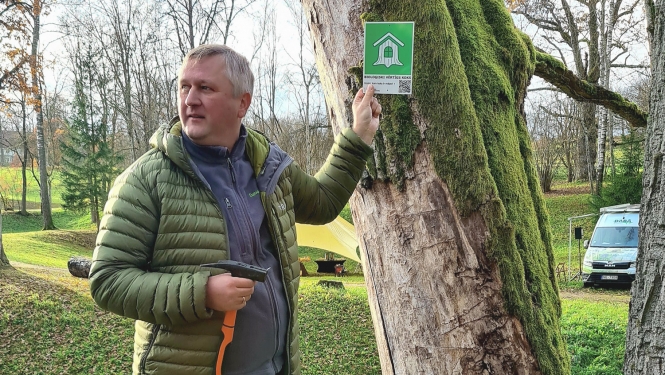 Dabas aizsardzības pārvaldes ģenerāldirektora p.i. Andris Širovs ar zīmi pie koka