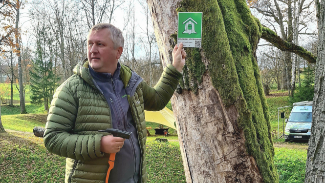 Dabas aizsardzības pārvaldes ģenerāldirektora p.i. Andris Širovs ar zīmi pie koka
