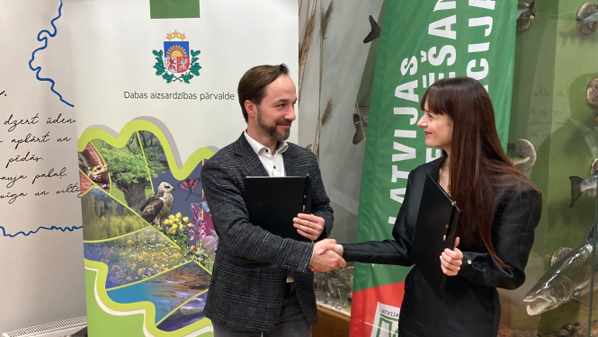 Latvijas orientēšanās federācijas prezidents Juris Žilko un Dabas aizsardzības pārvaldes ģenerāldirektore Laura Anteina paraksta sadarbības memorandu.