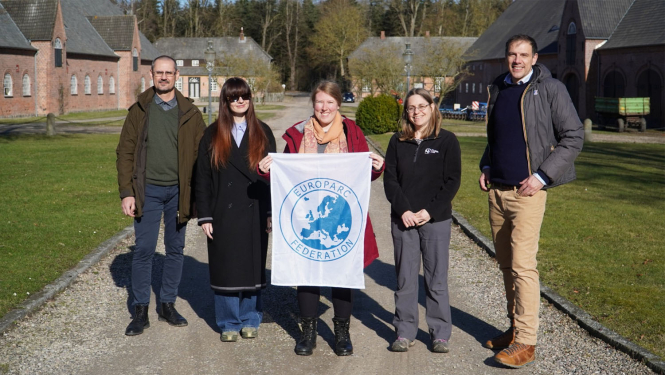 5 smaidoši cilvēki tur karogu ar EUROPARC logo