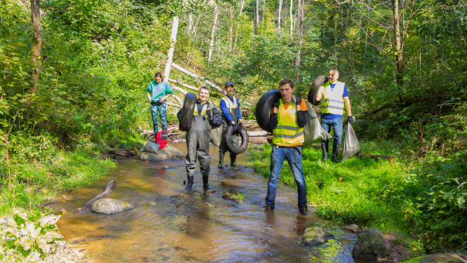 Cilvēki aizvāc riepas no upes gultnes.