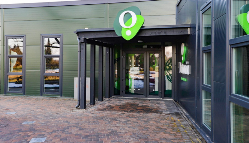 Vides izglītības centra BOTANIA galvenā ieeja. Bruģēts segums vienā līmenī ar durvīm. Durvis automātiski atveras.