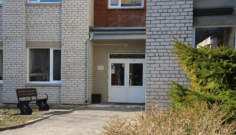 Divu stāvu, baltu silikāta ķieģeļu ēka ar stiklotām divviru durvīm.