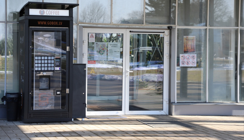 Stiklota ēkas fasāde ar divviru stikla durvīm, kurām viena puse atveras automātiski.