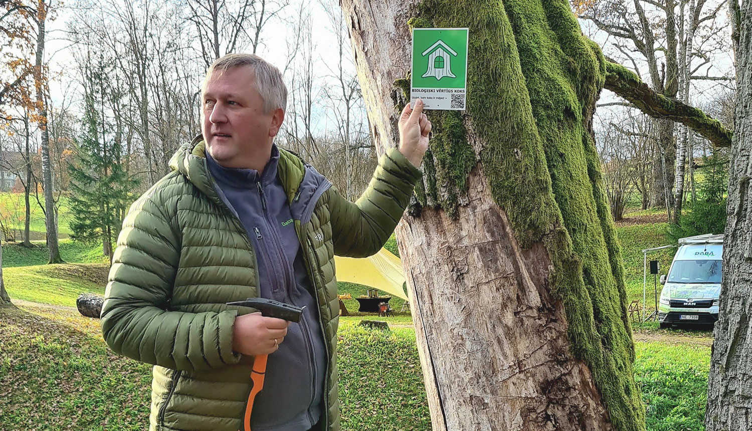 Dabas aizsardzības pārvaldes ģenerāldirektora p.i. Andris Širovs ar zīmi pie koka