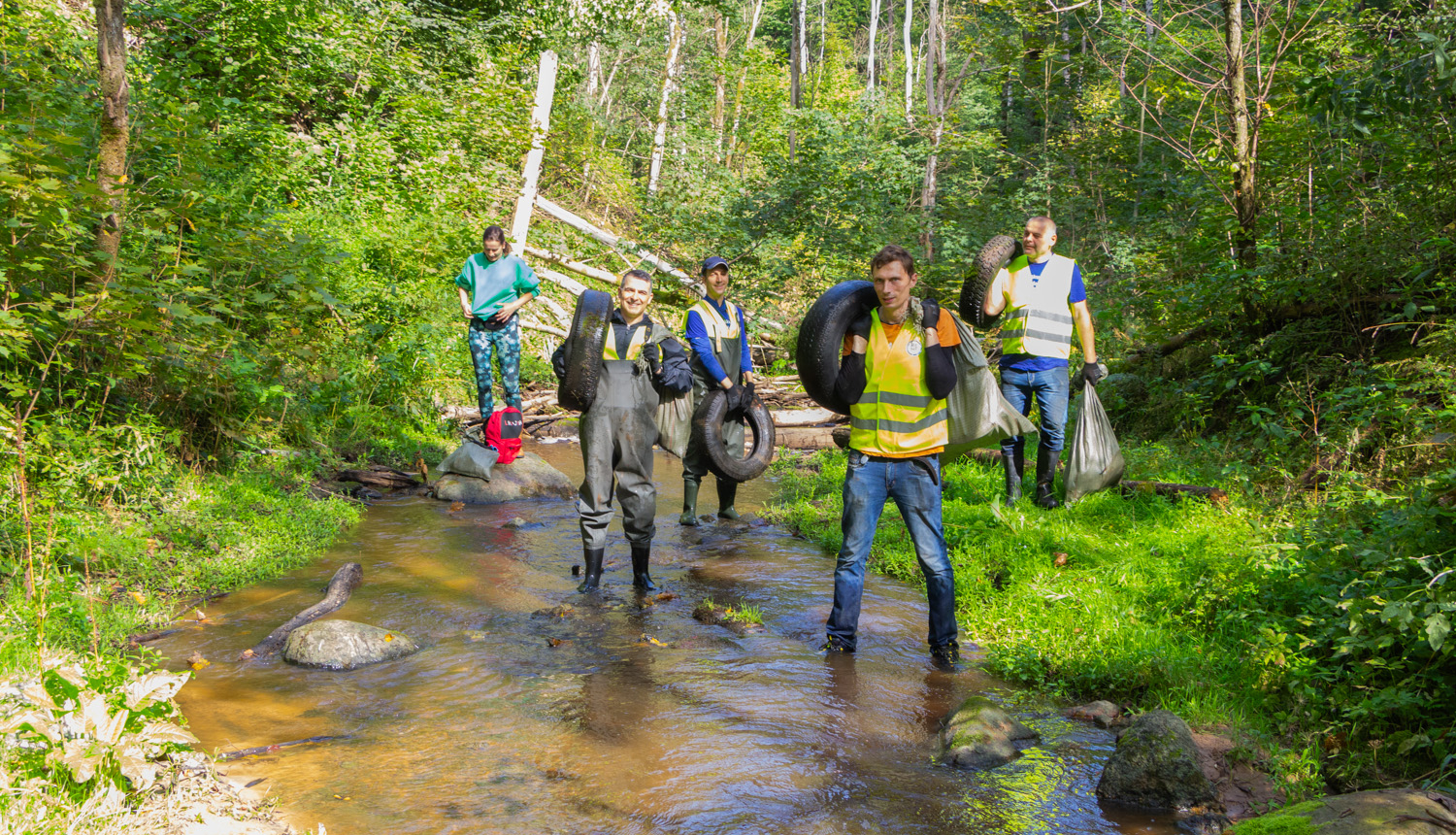 Cilvēki aizvāc riepas no upes gultnes.