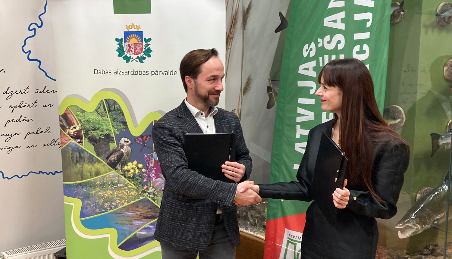 Latvijas orientēšanās federācijas prezidents Juris Žilko un Dabas aizsardzības pārvaldes ģenerāldirektore Laura Anteina paraksta sadarbības memorandu.